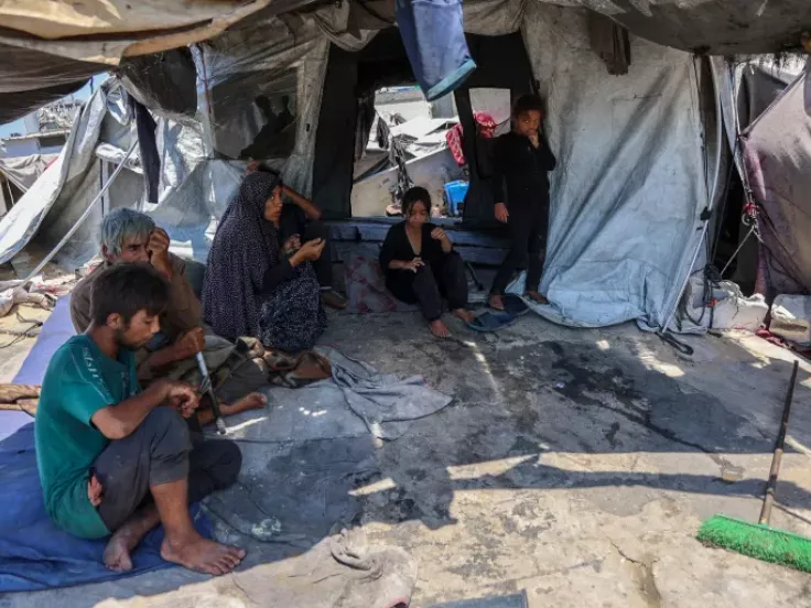 Members of a Palestinian family sit outside their tent in the Daraj neighbourhood in Gaza City [Omar Al-Qattaa/AFP]
