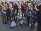 Palestinians stand next the body of a woman who was hit by a truck while attempting to reach a humanitarian aid convoy moving along the Morag corridor near Rafah, in the southern Gaza Strip, Monday, Aug. 4, 2025. (AP Photo/Mariam Dagga)
